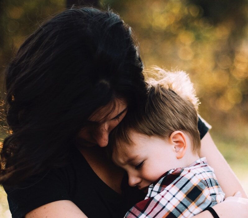woman hugging boy on her lap